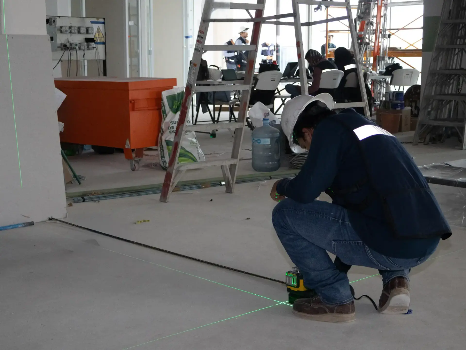 Técnico nivelando trazos eléctricos con láser en obra